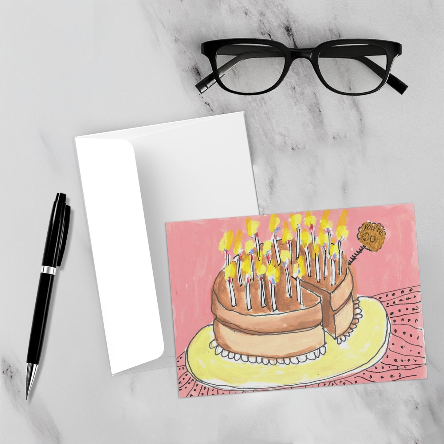 Mockup display showcasing the front of the greeting card You're 60! lying on a gray marble surface along side a white envelope, a pair of black reading glasses and a black pen.