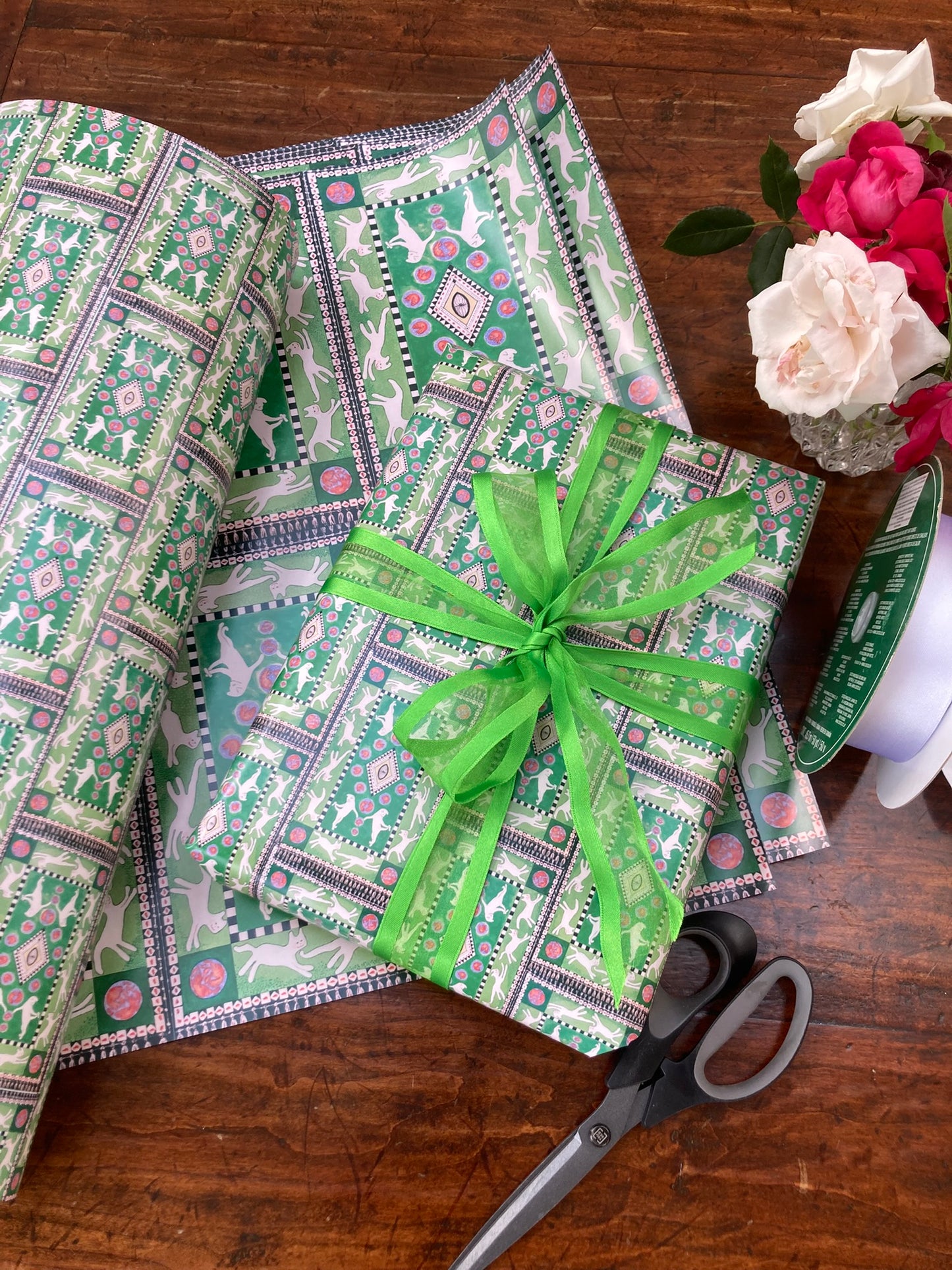 mockup of Presentation Cats gift wrap with wrapped box with green bow atop design on back and front.