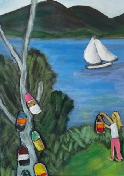 Buoy Tree shows a girl standing on green grass about to hang a colorful lobster buoy on a tree already decorated with some. In the back ground there is a sailboat in the ocean and the mountains of Acadia on the mainland.
