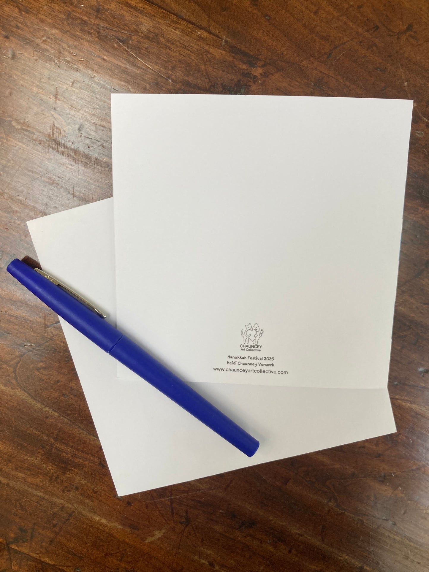 White card with a blue pen on a wooden surface