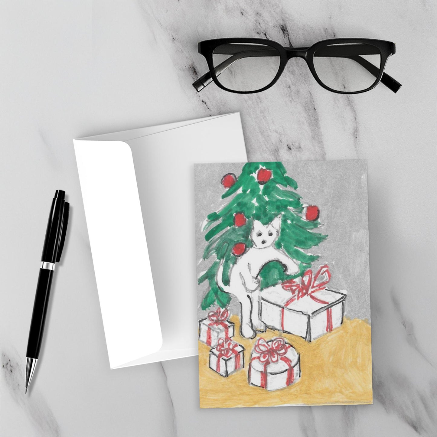 Mockup of the front of the Christmas card called Little Doings For Christmas lying flat on a grey marble surface with a white envelope, a black pen and a pair of black reading glasses.