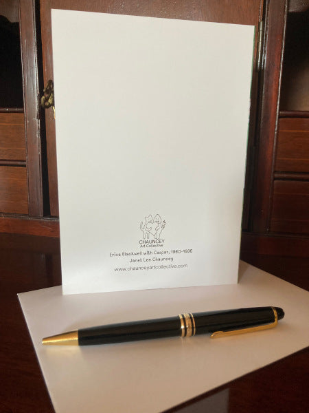 Mockup of the back of the greeting card along with the pen and envelope atop a wooden desk