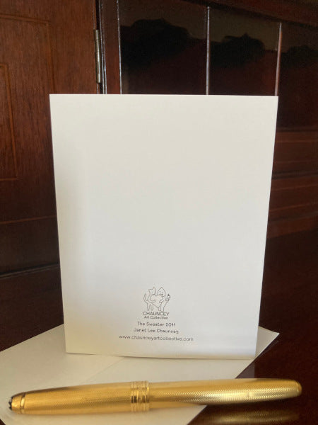 A mock up of the rear of the card is placed upright on a wooden desk with its envelope below.