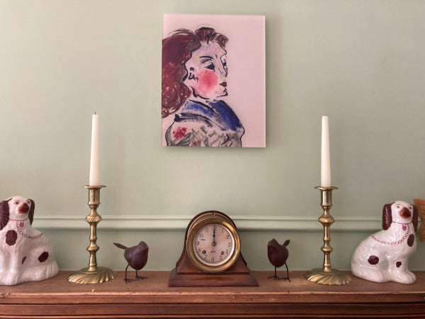 Portrait titled Jeanette seen hanging centered on a light green wall above a mantle with to various objects to show the acrylic print staged in a home setting.