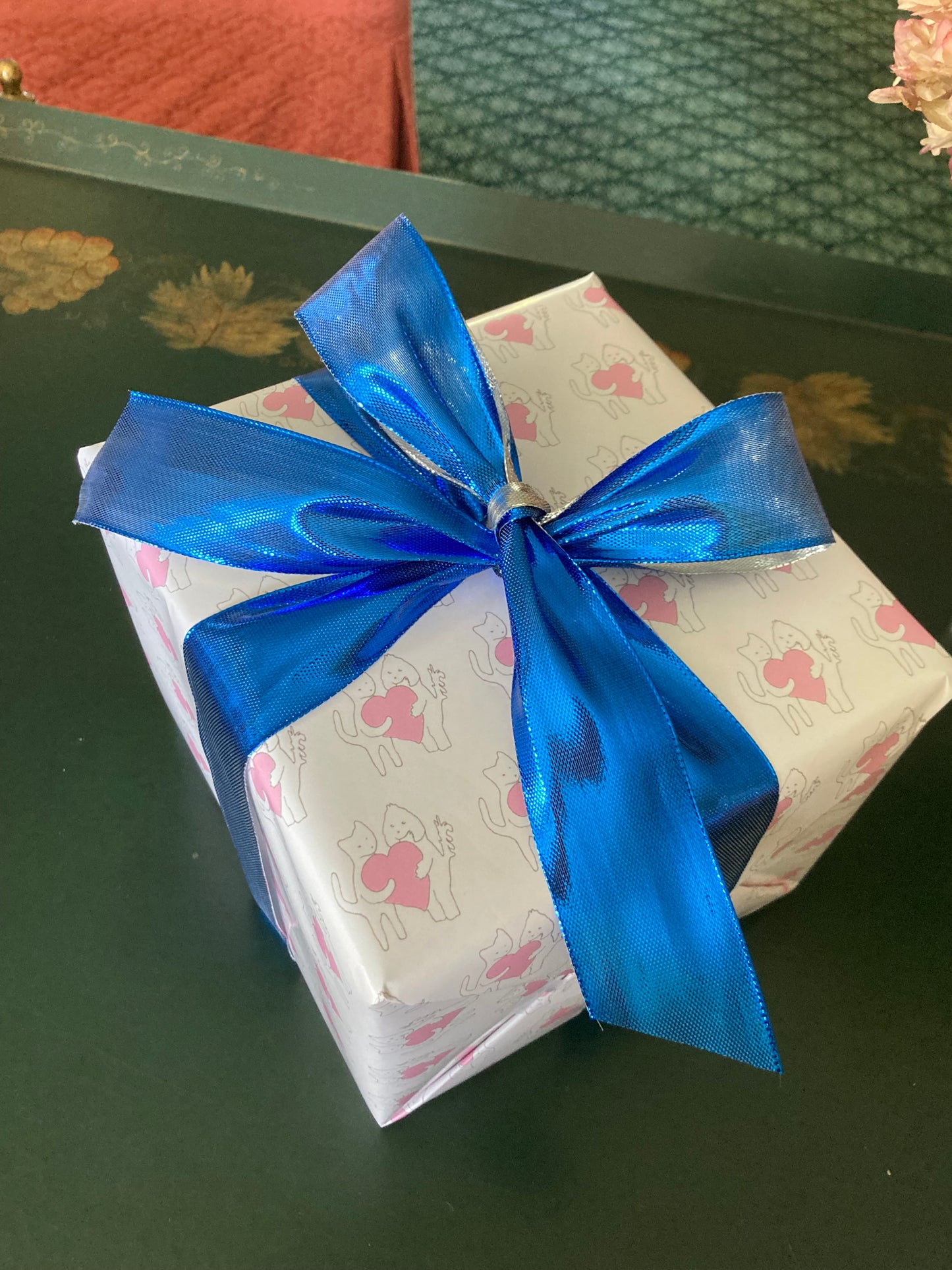 A gift wrapped in Sharing A Big heart wrapping paper looks festive with a blue ribbon.