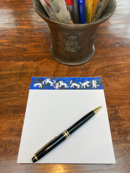 Mock up of Playful Dogs notepad, the white paper and blue banner with doggies stands out on a wooden table.