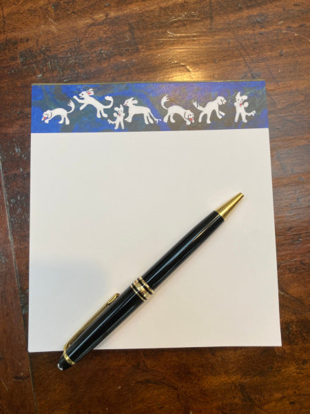 Mockup of Playful Dogs notepad on a wooden table with a black pen.