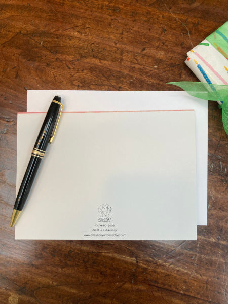 The back and envelope of the birthday card You're 50! are featured on a wooden table with a black fountain pen.