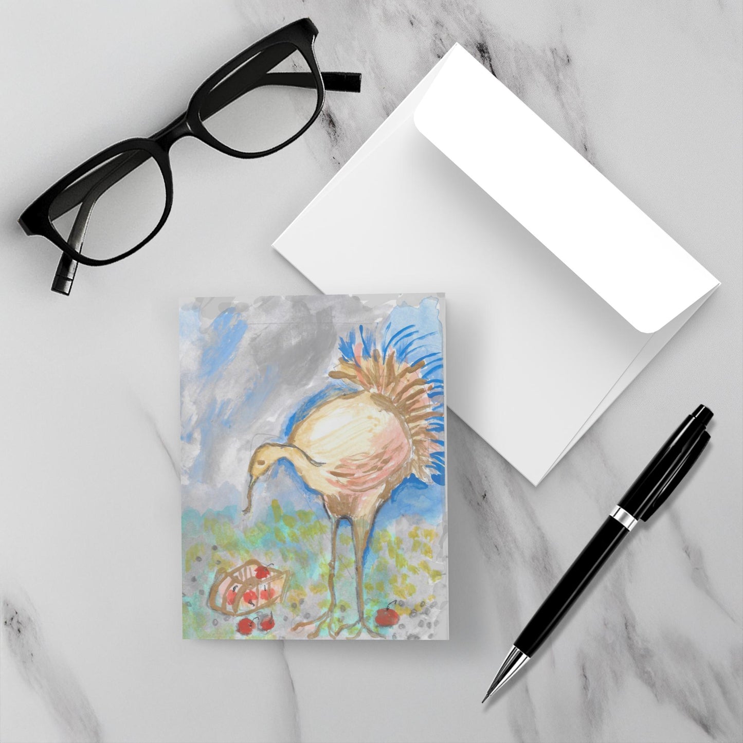 Mockup of the greeting card Vermont Turkey which shows the front of the card with the turkey and basket of apples, a white envelope, a pair of black reading glasses and a black pen all resting on a gray marble counter top.