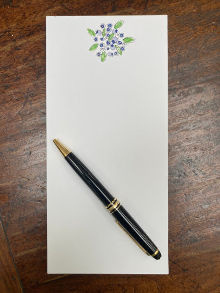 The pretty blueberries really stand out against the white paper on this magnetic notepad. It is placed on a wooden table with a fountain pen resting on its front page.