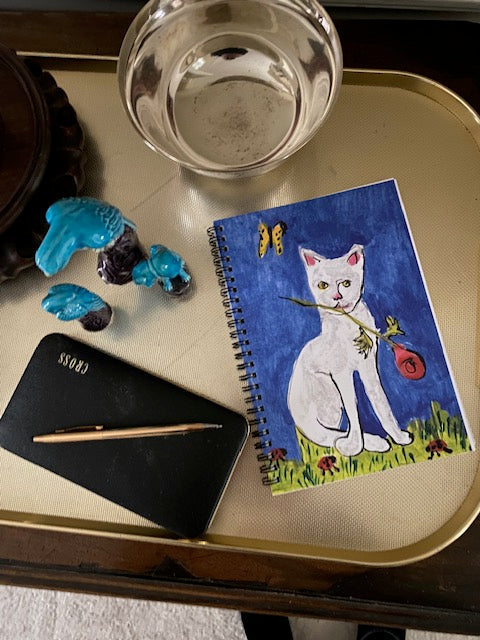 Another mockup of Caspar and Suddenly notebook where the yellow butterfly is near some blue bird figurines.