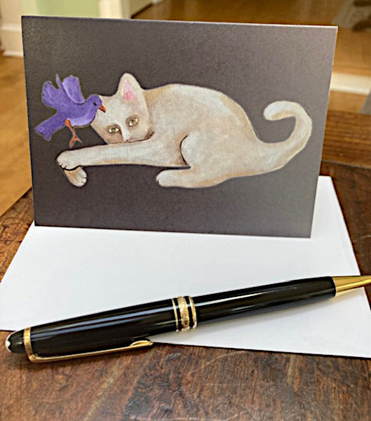 Mockup of Cat With Bird notecard and its envelope sitting on a wooden table with a fountain pen.