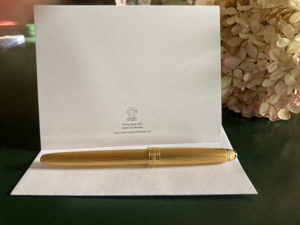 Mock up of the back of greeting card Falling Leaves showing the title, Chauncey Art Collective logo and a gold fountain pen.
