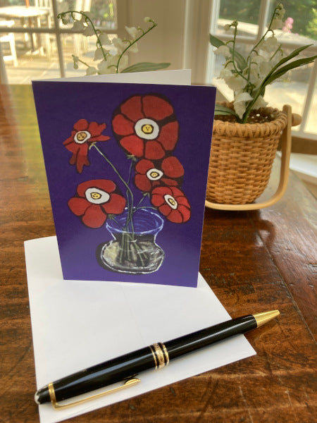 The front of the notecard Flowers From the Garden is sitting on a wooden table with the envelope and a basket of flowers is in the background.