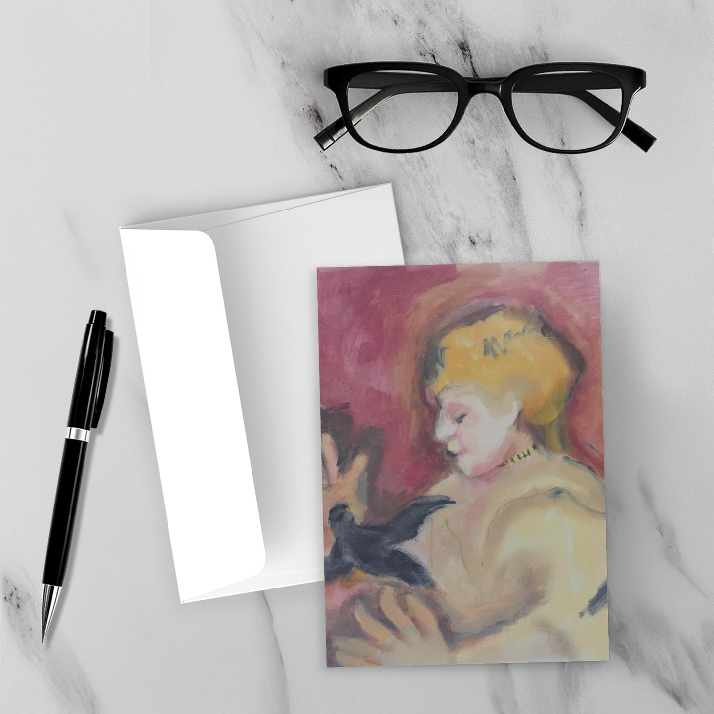 Mock up of the greeting card shows Girl With Bird facing the camera on a white marble backdrop accompanied by the envelope, reading glasses and a pen.