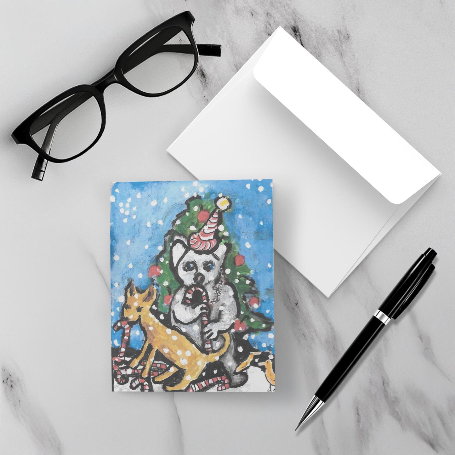 Mockup of the Christmas greeting card titled Astonishing Creatures With Tasty Treats which displays the front of the card, it's white envelope, a pair of black reading glasses and a black pen all lying on a gray marble surface.