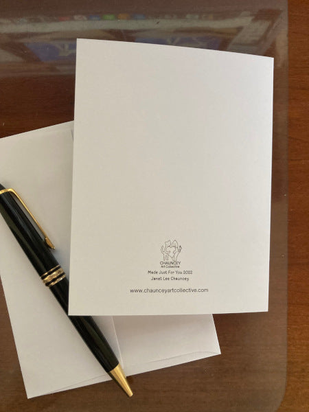 Photograph of the back of the greeting card Made Just For You which shows the back of the card lying flat on the desk top with white envelope and black pen.