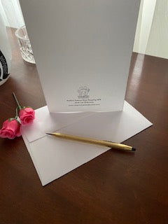 A mockup of the back side of the card with its envelope and a gold pen atop a wooden table.