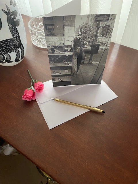 Mock up of the card on a wood table with the envelope and a gold pen.