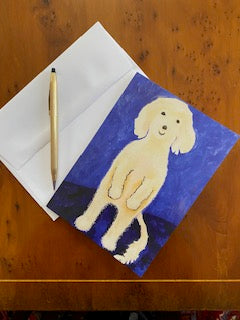 Front of greeting card Ollie Stands Up displayed on brown desk top at an angle with an envelope and a gold pen.