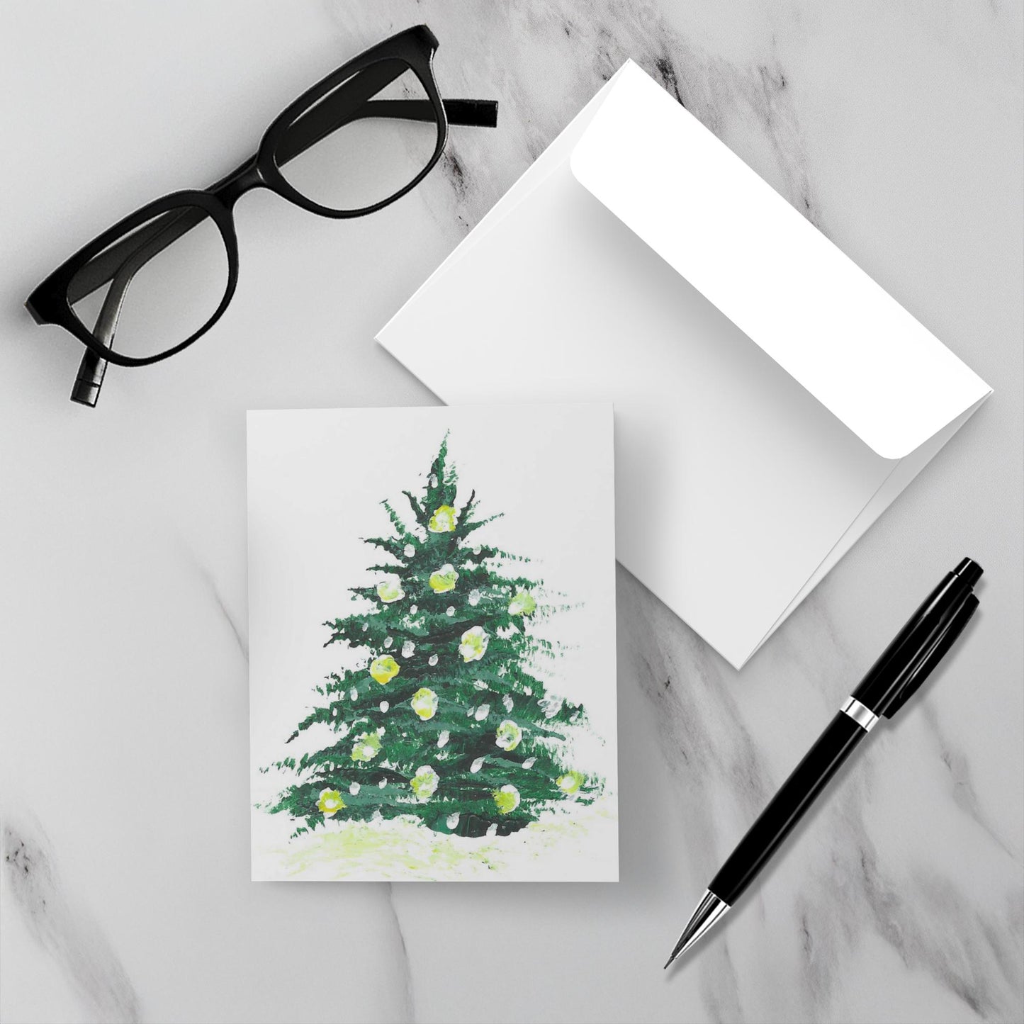 Mock up of the front of Outdoor Lights Christmas card with its envelope on a marble background with a pen and reading glasses.
