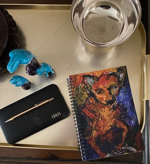 Mockup of the notebook on a golden tray with blue dog figurines and a silver bowl nearby,