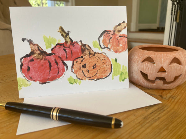 Mock up of the front of Pick Me Pumpkin in the pumpkin patch sitting next to a terra-cotta pumpkin.