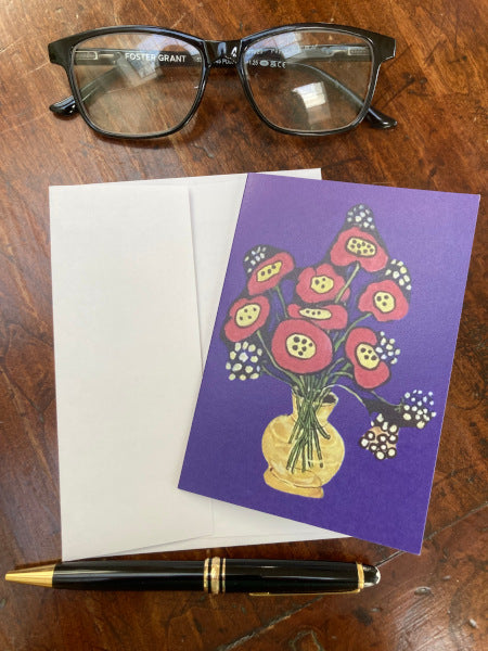 Mockup of the floral themed notecard sitting on a wooden table with reading glasses and a pen