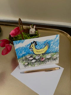 Front of the card Prissy Egg Walk displayed on a gold colored tray with a little Easter Basket that holds a little Easter bunny ornament and some red flowers in the background and a white envelope and a gold pen in the foreground.