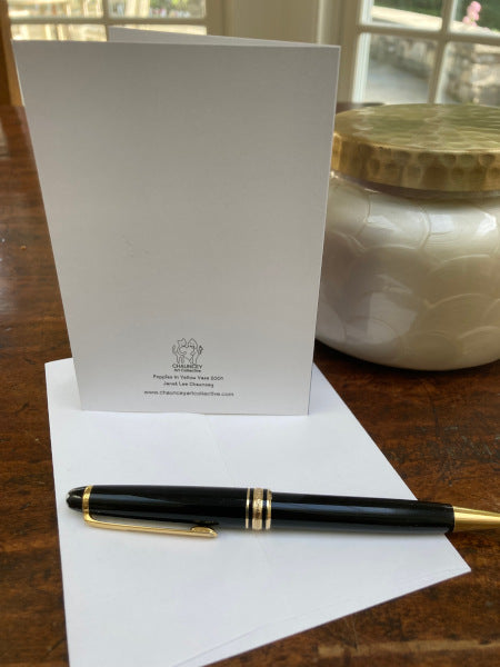 Mock up of the back of the notecard and an envelope on a wooden table with a pen.