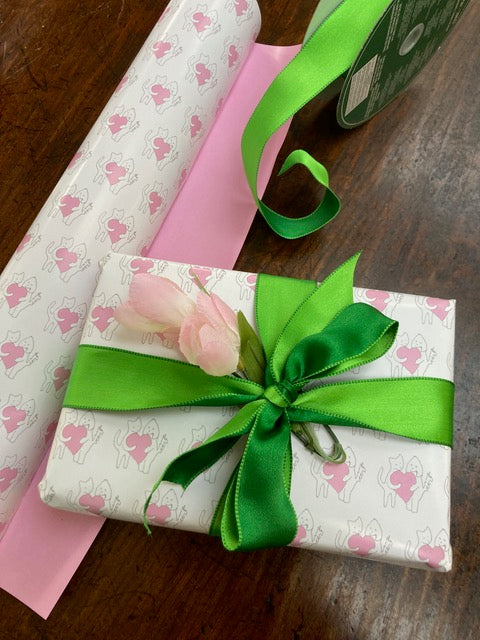 Sharing A Big Heart wrapping paper is used to wrap a present which is decorated with a bright green ribbon and pink roses.