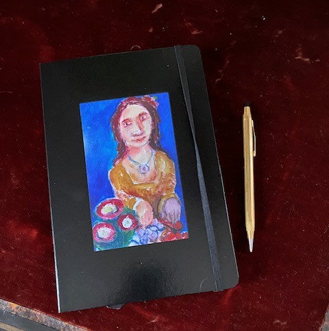 Mockup of Tasty Fruit journal with a gold pen on a red velvet surface. The painting shows a sweet girl preparing her food tray.