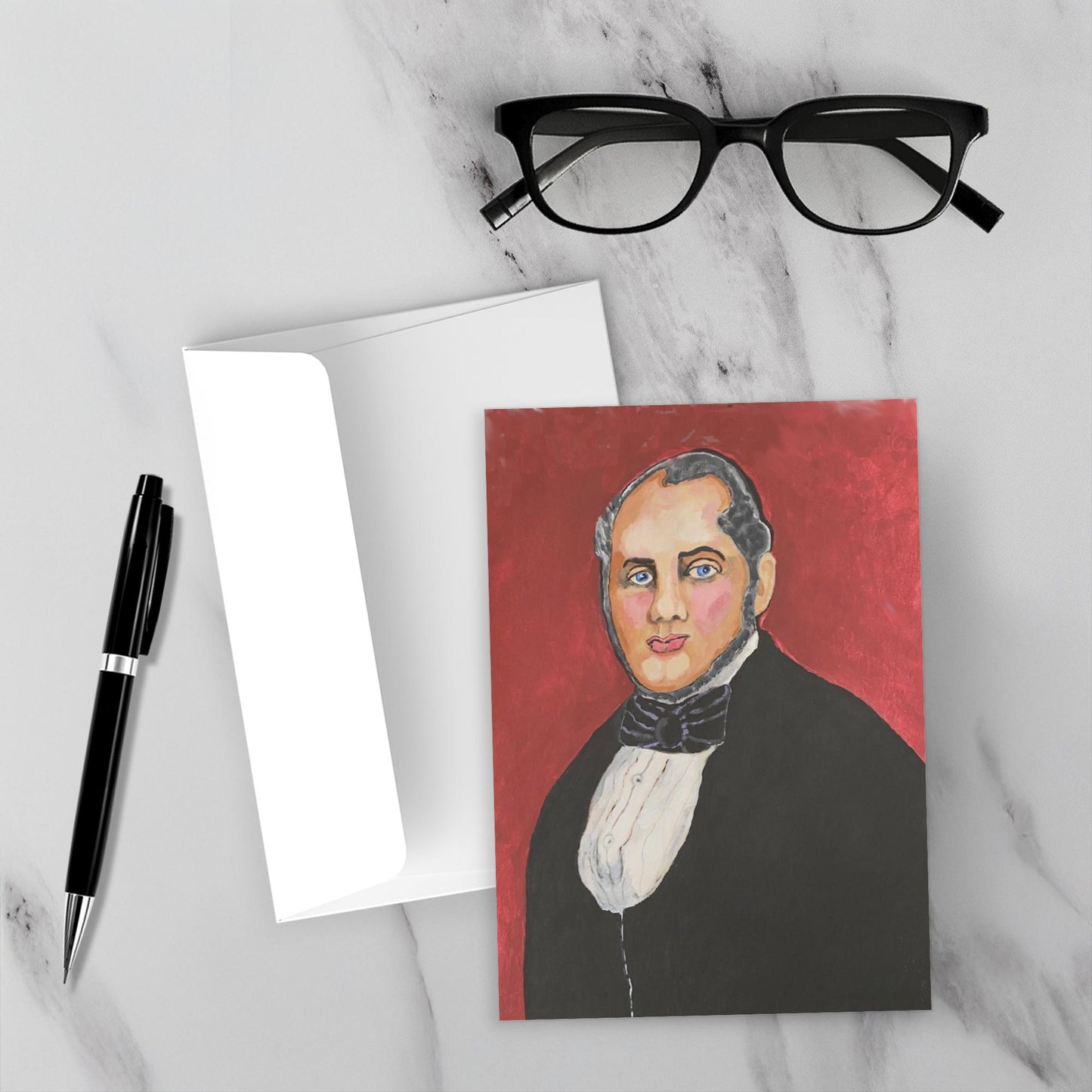 Mockup of greeting card, the Good Doctor lying on grey marble topped surface with white envelope, black reading glasses and black pen.