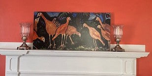 "Turkey Talk" mockup. The metal print is propped on a white mantle against orange wall with two metal-footed glass hurricanes on either side.