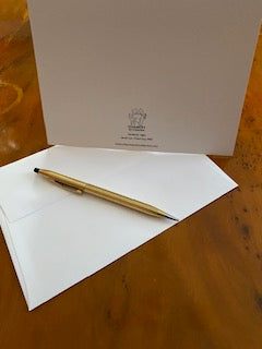 The back of the photo greeting card Vermont Light is displayed on a brown burled desk top with a white envelop and a gold pen.