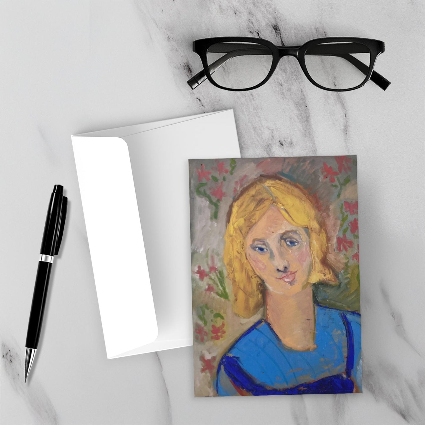 Mockup of the colorful Yellow Haired Girl on a white marble backdrop with the envelope, black pen and reading glasses.
