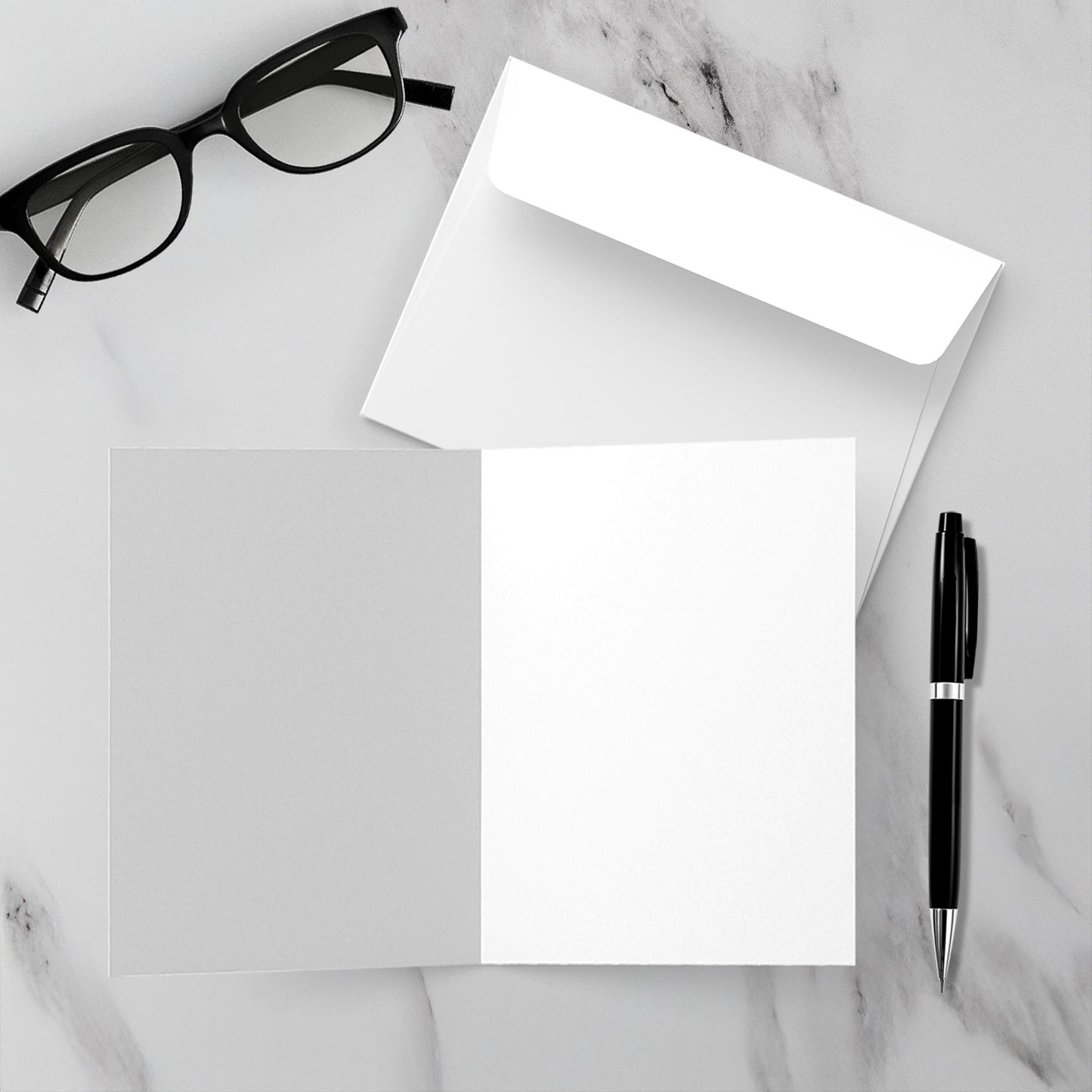 A mock up of the white envelope and blank inside of Firepit Fun! greeting card set on a white marble background.