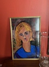 Portrait of a woman in a blue dress framed in a gold frame on a red wall.