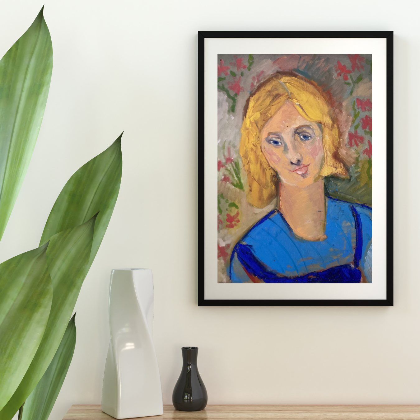 Yellow Haired Girl art print is in a matted black frame against a white wall. Her portrait offers a sweet expression and the bold blue of her dress offsets her glowing blonde hair beautifully.