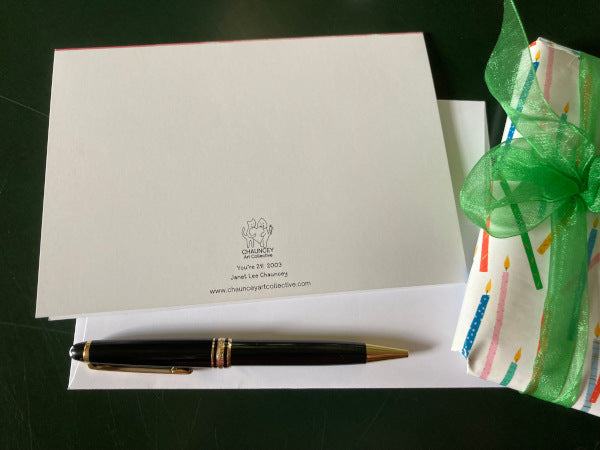 The back of the birthday card You're 21! along with it's envelope are shown along with a wrapped gift and a black fountain pen.
