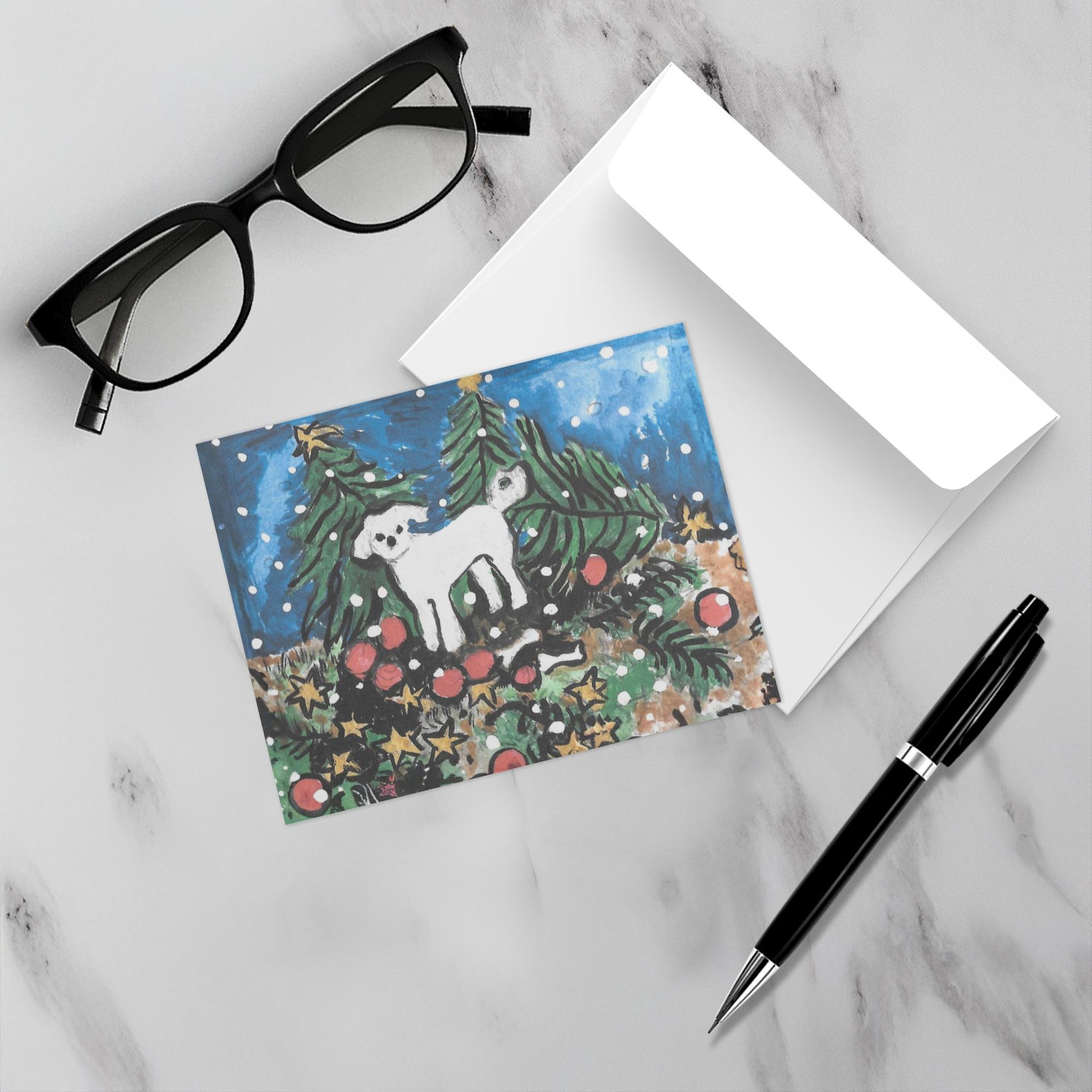 The front and back of the holiday greeting card The Wind Did it are sitting on a marble surface with a black pen and eyeglasses. Part of Chauncey Art Collective's Christmas card collection.