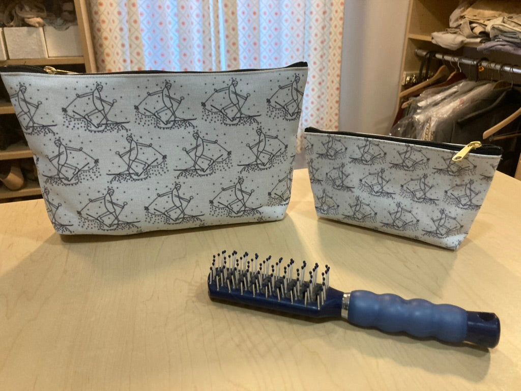 Two Accessory pouches with Trail Blazer pattern on wooden surface with a blue hairbrush.
