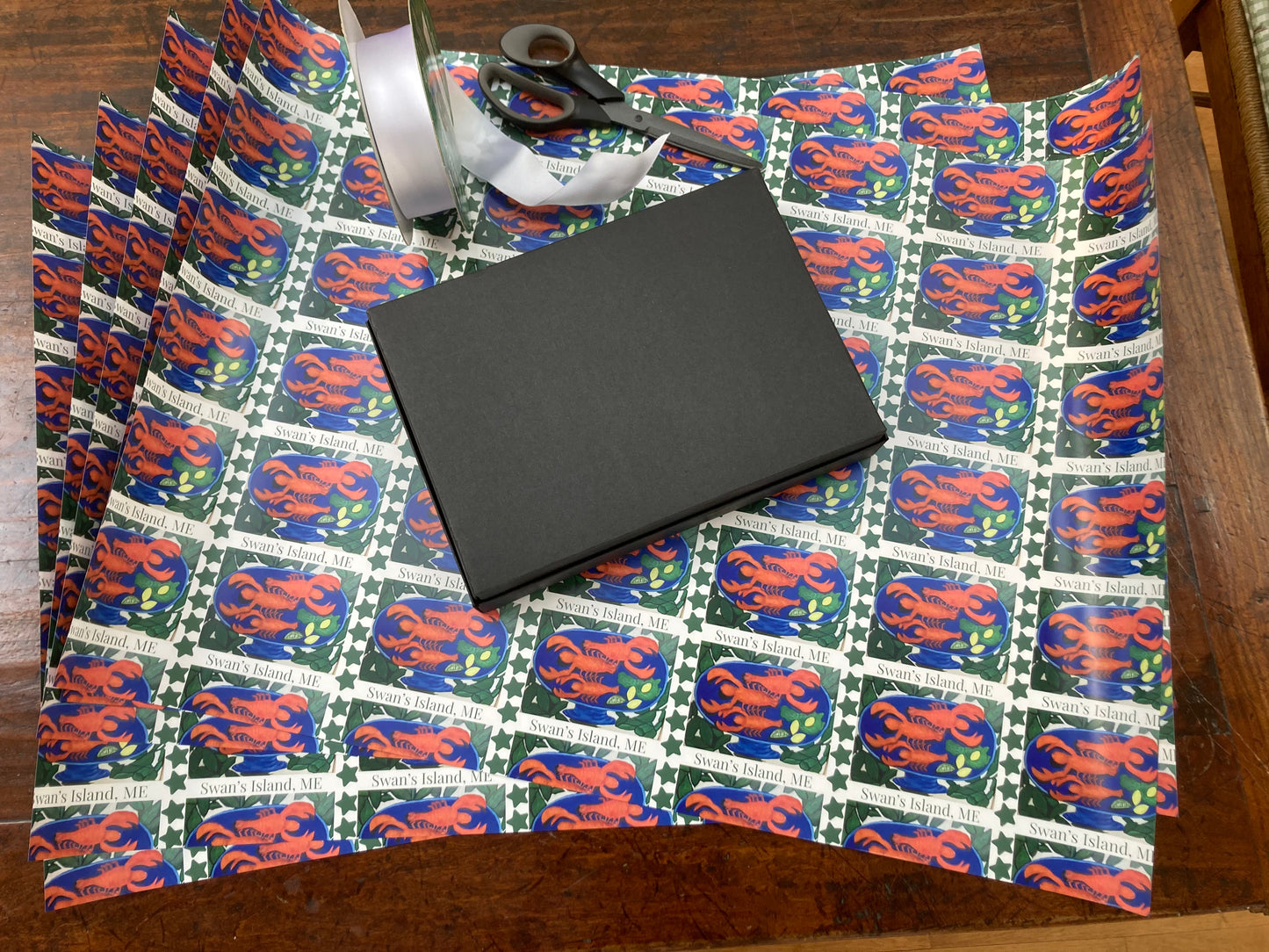Mock up of gift about to be wrapped in Swan's Island Lobster double sided wrapping paper, 5 sheets shown.