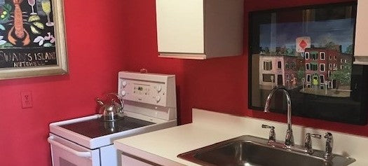 Original acrylic painting Back Bay Street by Gretchen Chauncey hangs over the kitchen sink. The room has fire engine red walls and white cabinets. Chauncey Art Collective stationery collection.