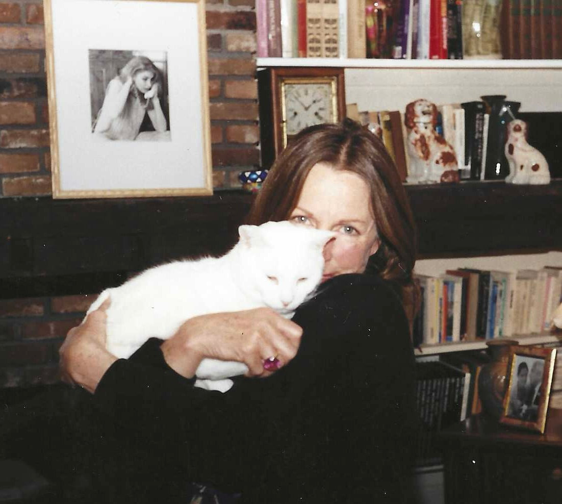 Janet Lee Chauncey lovingly embracing her white cat Caspar.