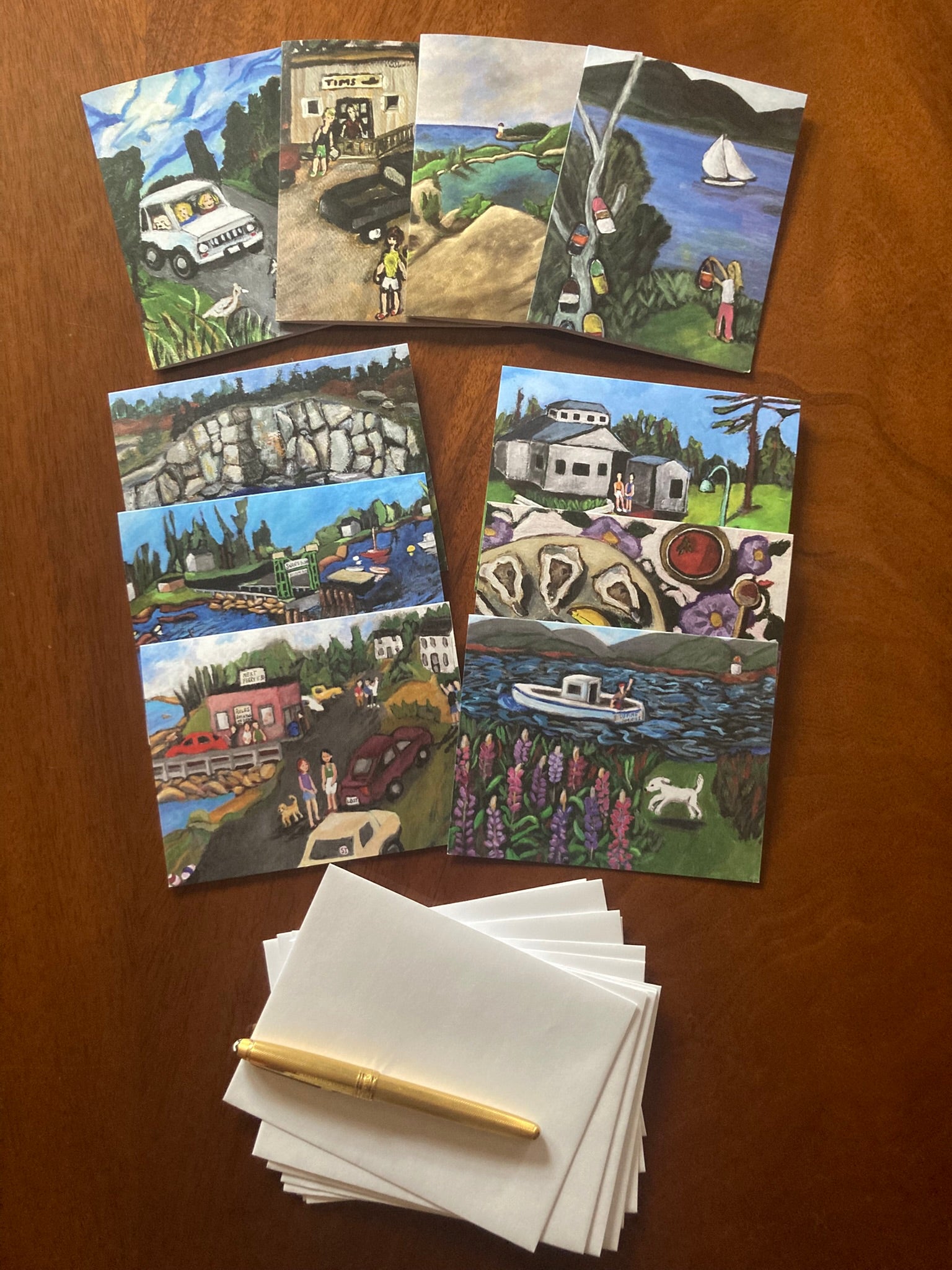 All ten cards of the Swan's Island greeting card set by Chauncey Art Collective are fanned out on a wooden table