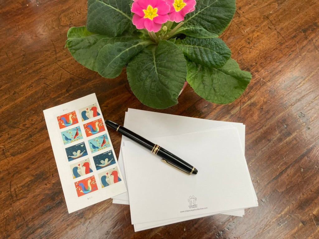 Potted plant, stationery items, and a pen on a wooden surface