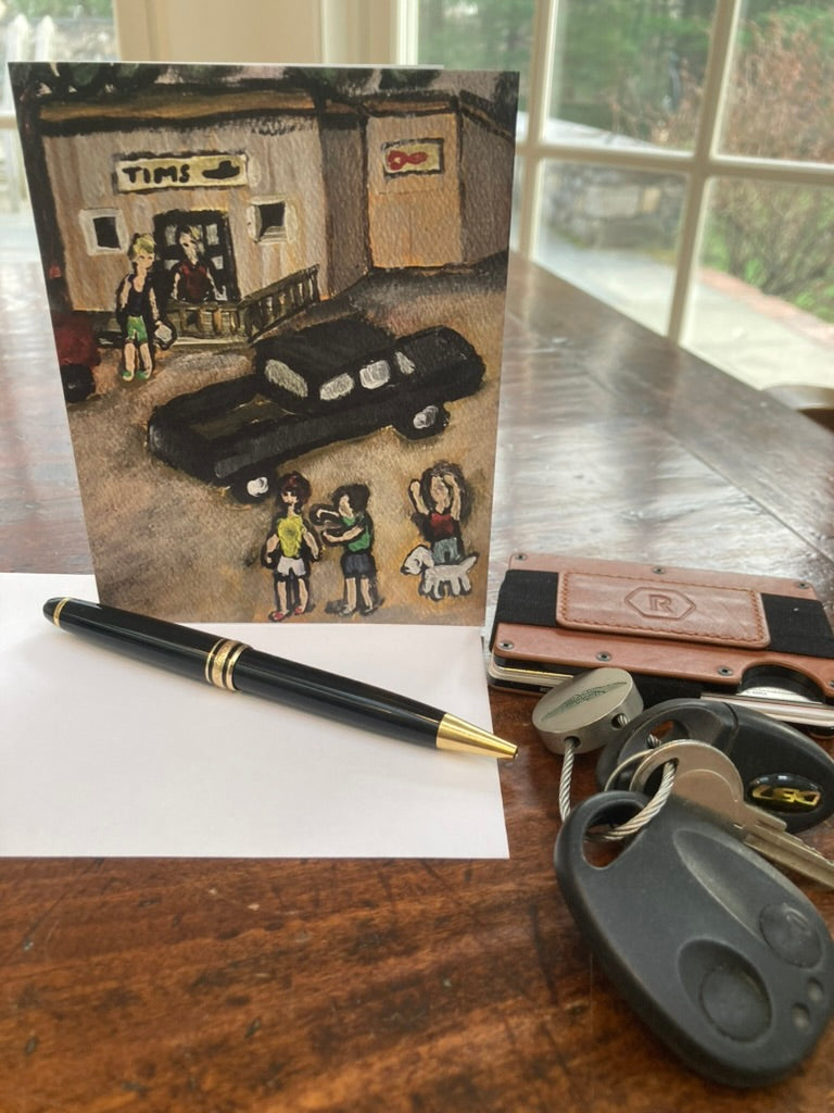 Greeting card of a car and people in front of an island store on a table with card with a pen and keys.