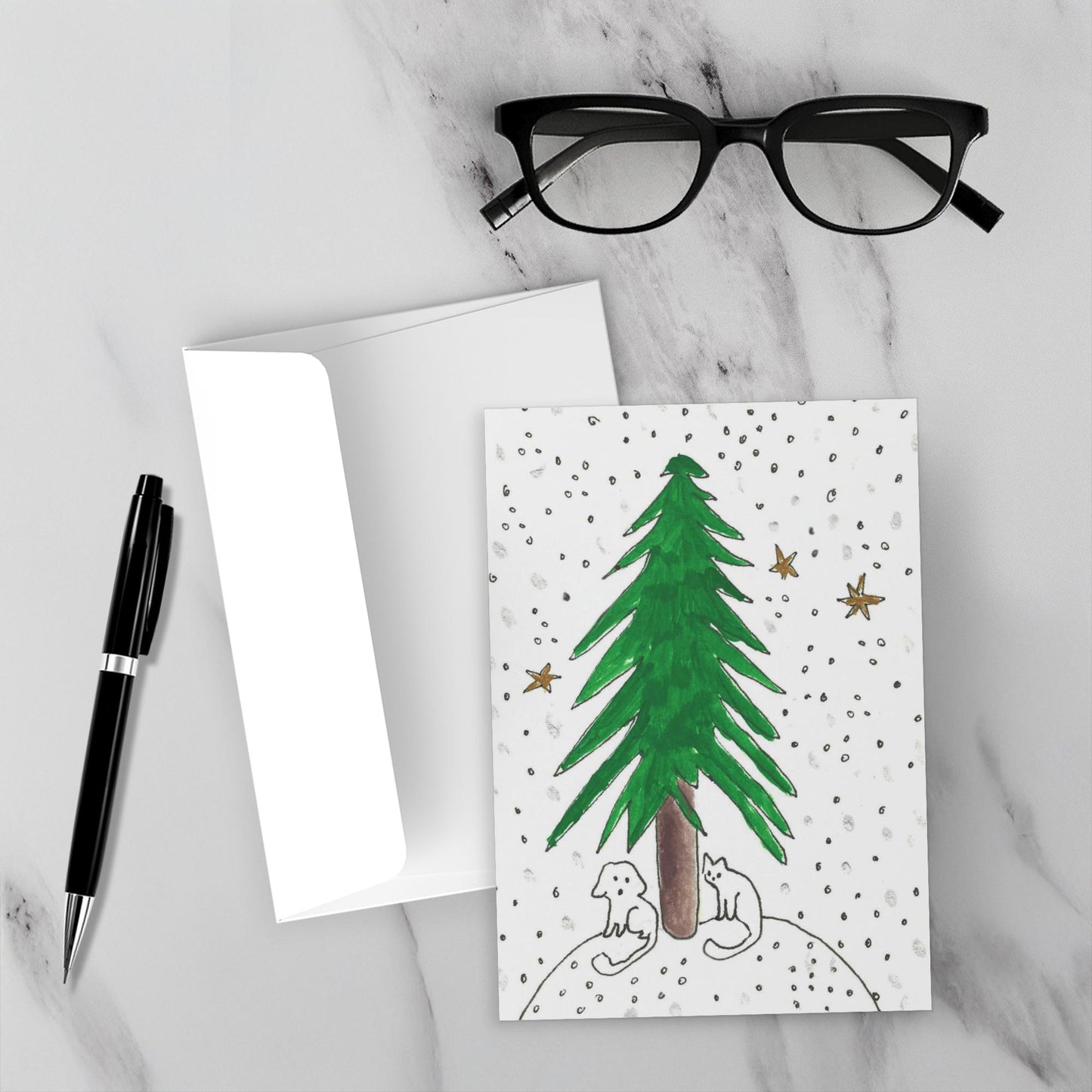 Greeting card with a green tree illustration on a marble surface with glasses and a pen.