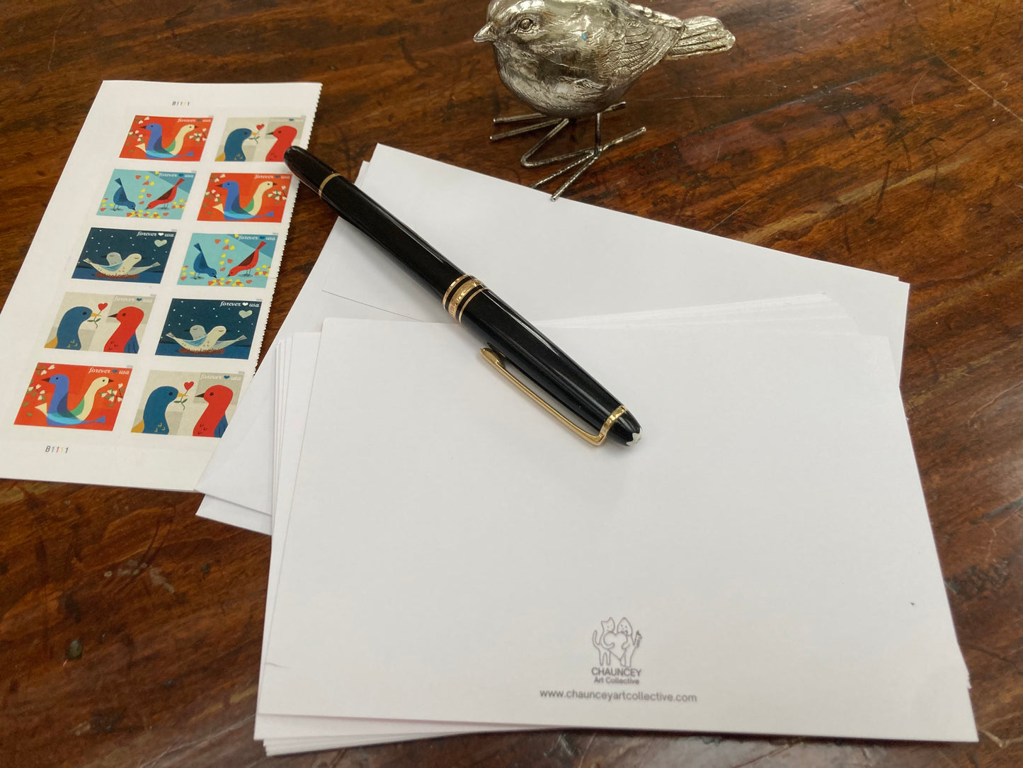 Fountain pen, letterhead paper, and stamps on a wooden surface